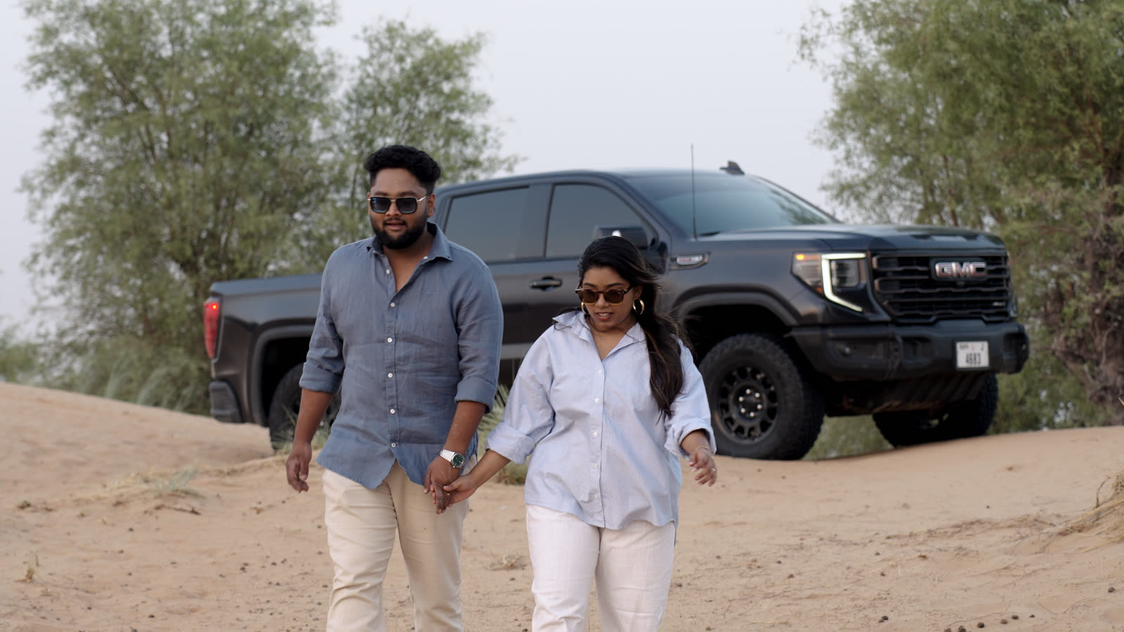 Vibha and Jishnu walking hand in hand in the desert