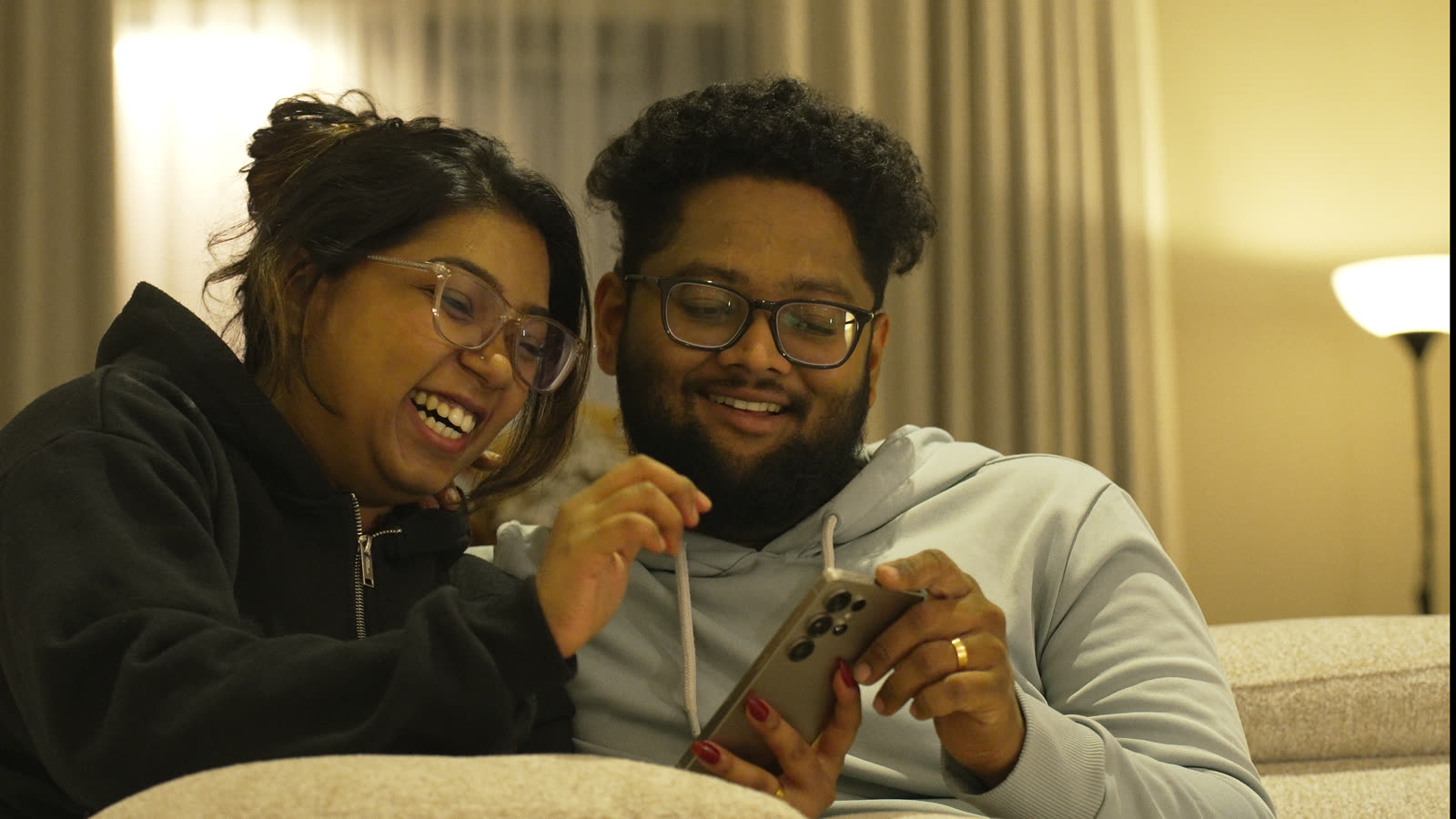 Vibha and Jishnu laughing together on the couch