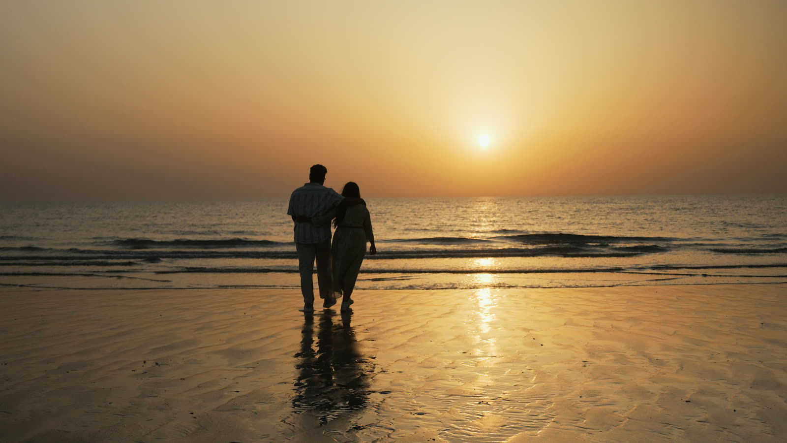 Vibha and Jishnu walking on the beach at sunset