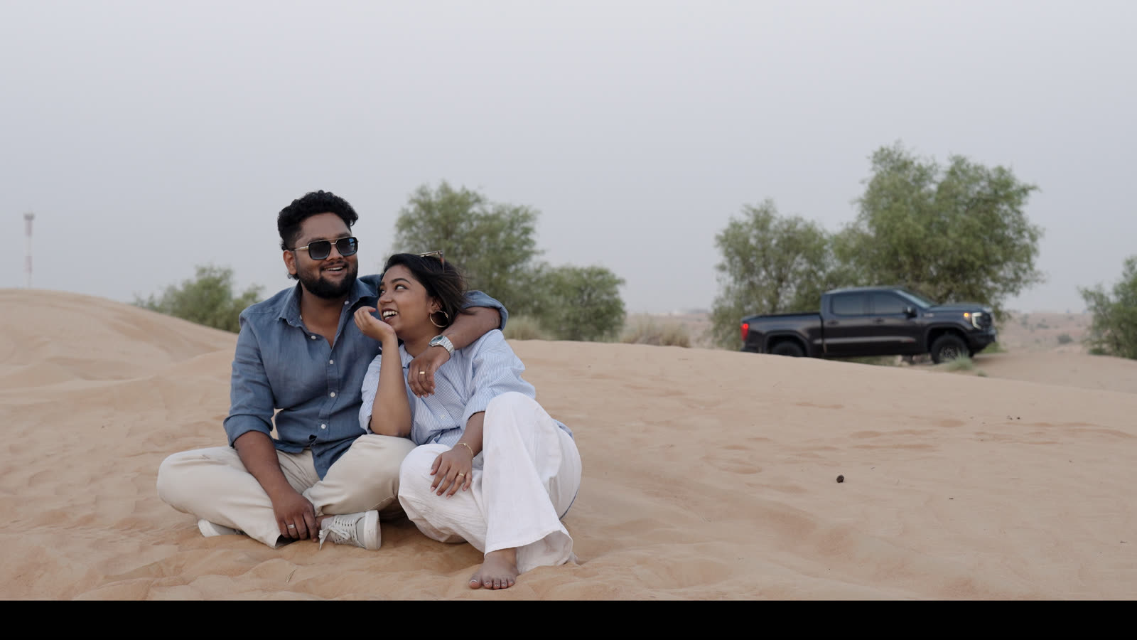 Vibha and Jishnu sitting together on a sand dune