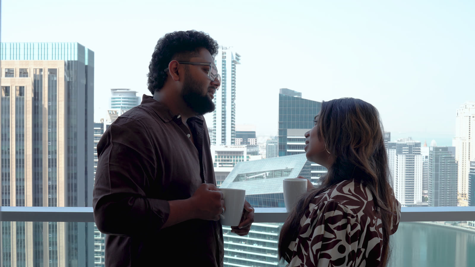 Vibha and Jishnu sharing coffee on a balcony overlooking the city